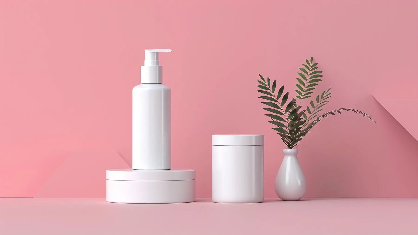 Minimal white skincare containers arranged on a soft pink background
