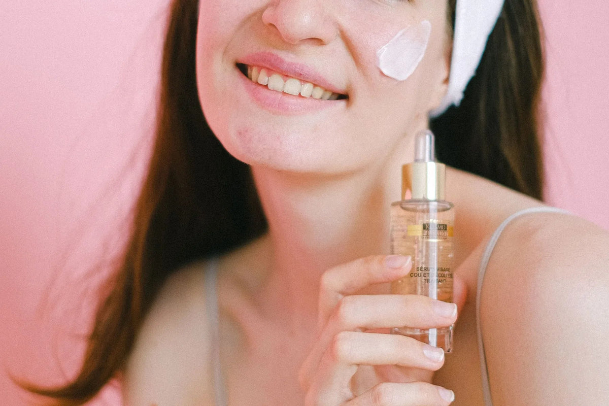 Woman applying skincare against a soft pink background