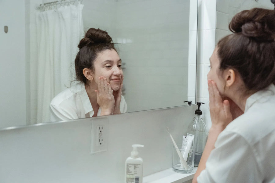 Woman applying skincare while looking in a bathroom mirror