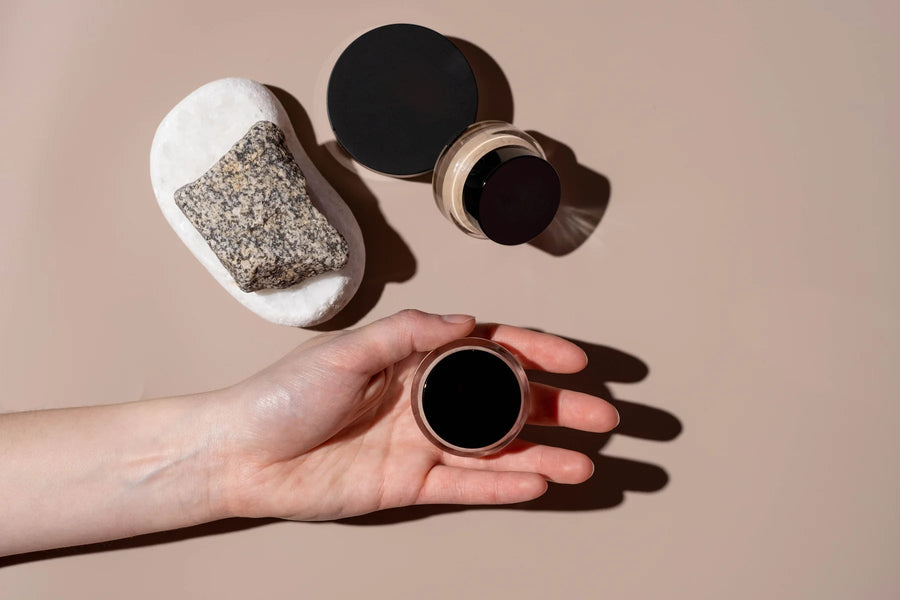 Hand inspecting an open makeup container beside cosmetic products
