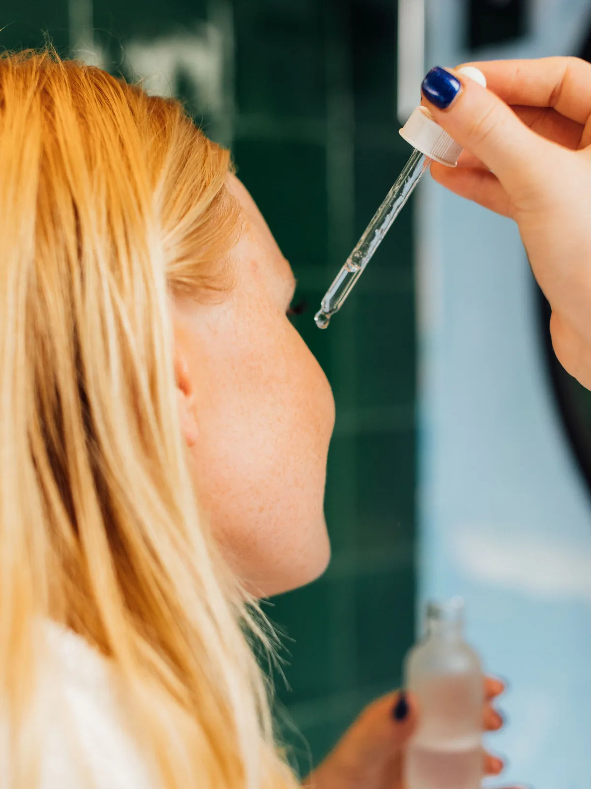 Woman applying a facial serum carefully with a dropper