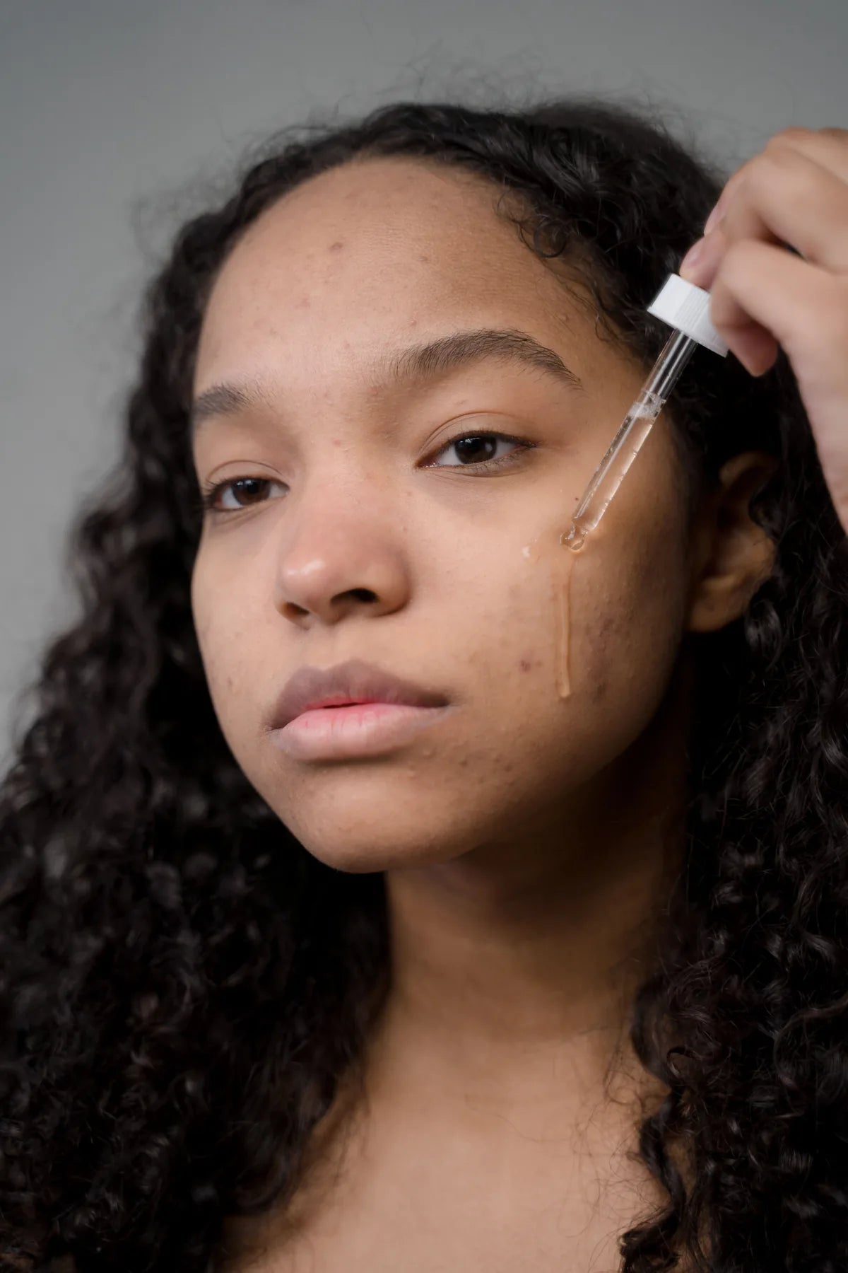 Woman applying a small amount of face serum with a dropper