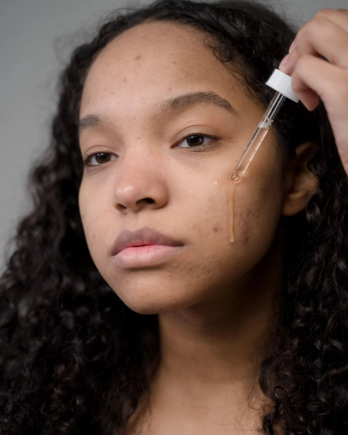 Woman carefully applying facial serum with a dropper