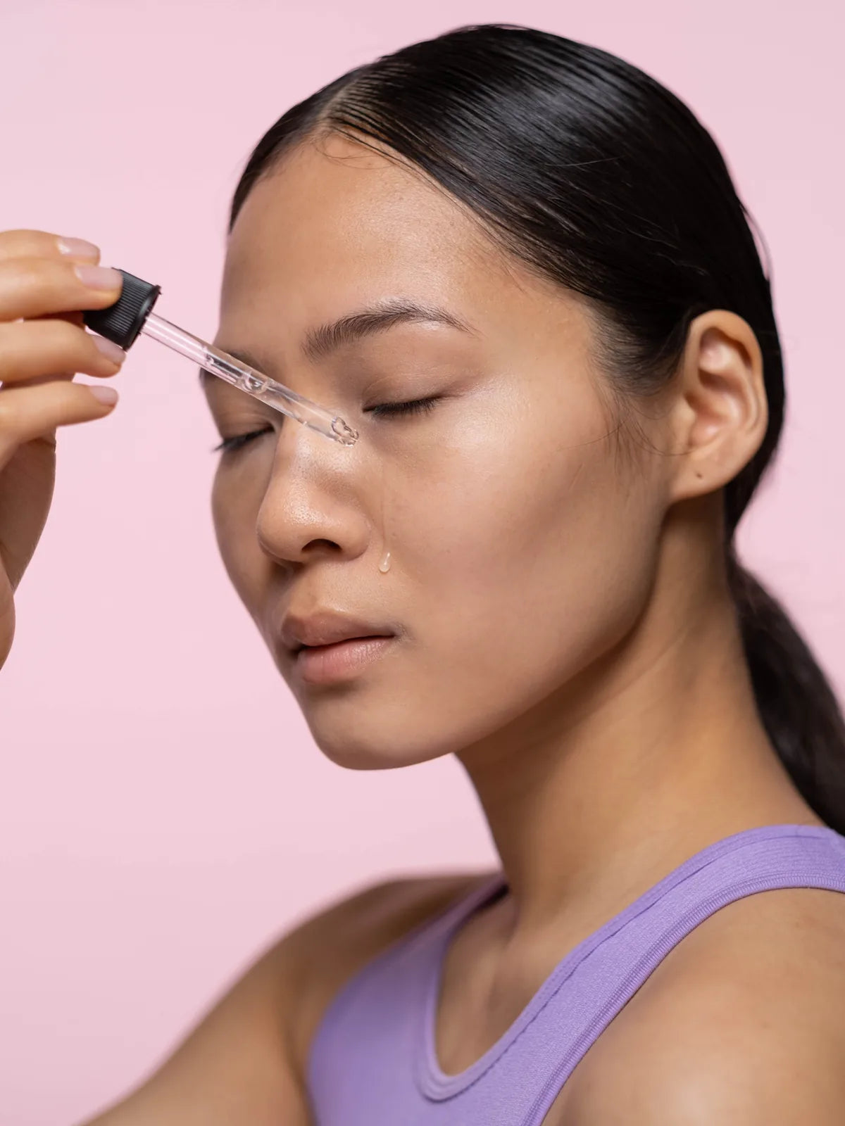 Woman applying a face serum carefully with a dropper