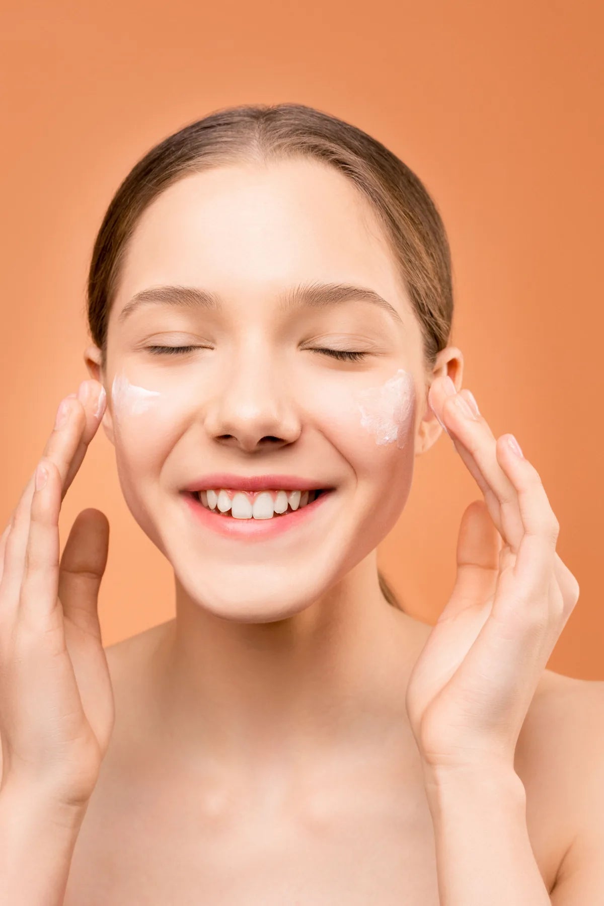 Woman applying moisturizer to both cheeks