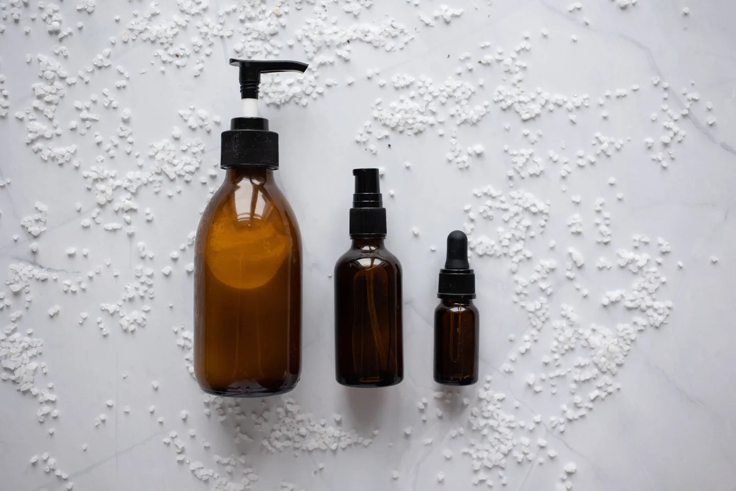 Three amber skincare bottles arranged on a clean white surface
