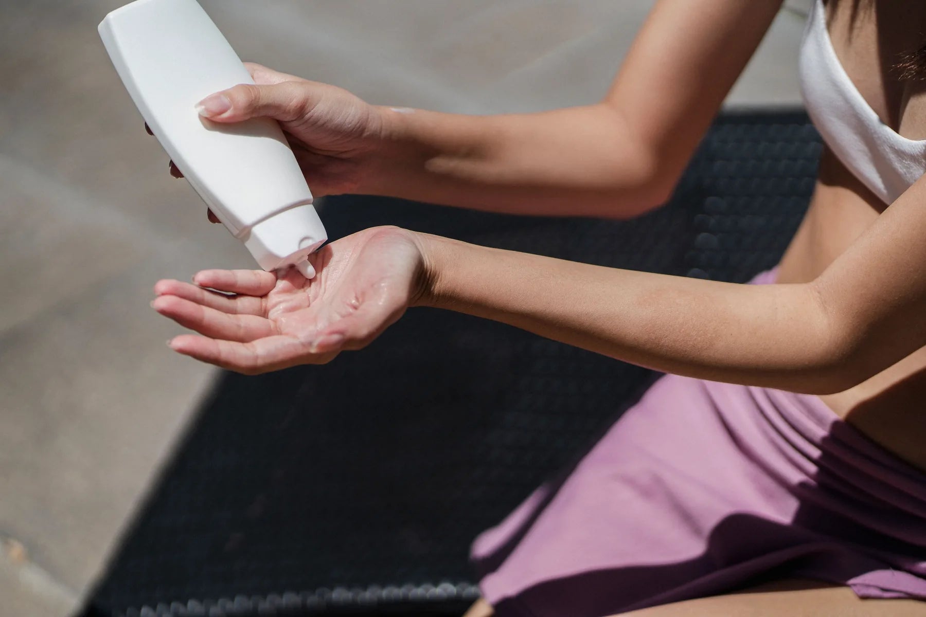 Woman dispensing sunscreen into her hand outdoors